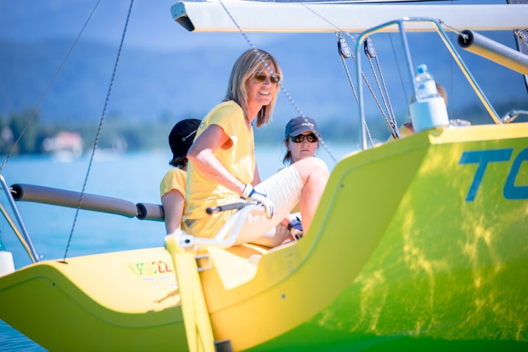 Zwei Frauen segeln bei sonnigem Wetter auf einem modernen Segelboot auf einem See.