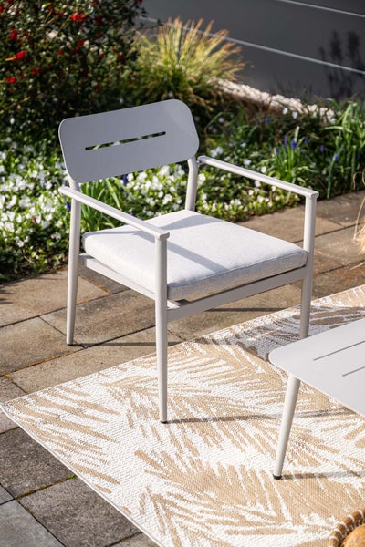 Gartenstuhl aus Metall mit Sitzkissen auf einer Terrasse mit Teppich im Aussenbereich.