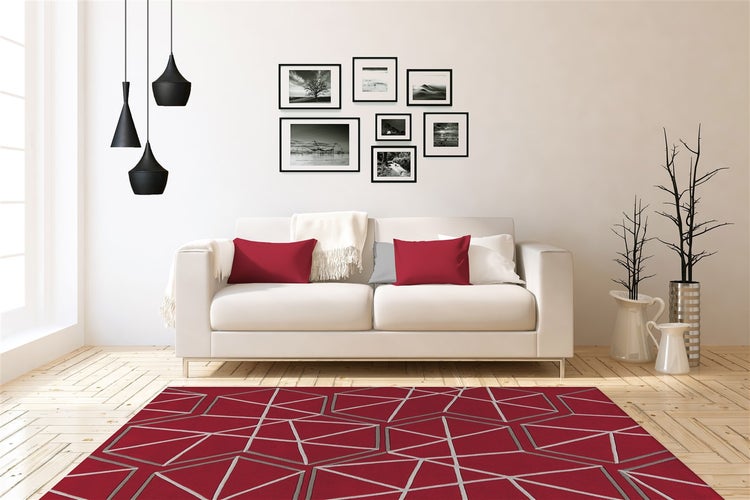 Wohnzimmer mit Sofa, Kissen, Wandbildern, drei Hängeleuchten und einem Teppich mit geometrischem Muster auf hellem Holzboden.