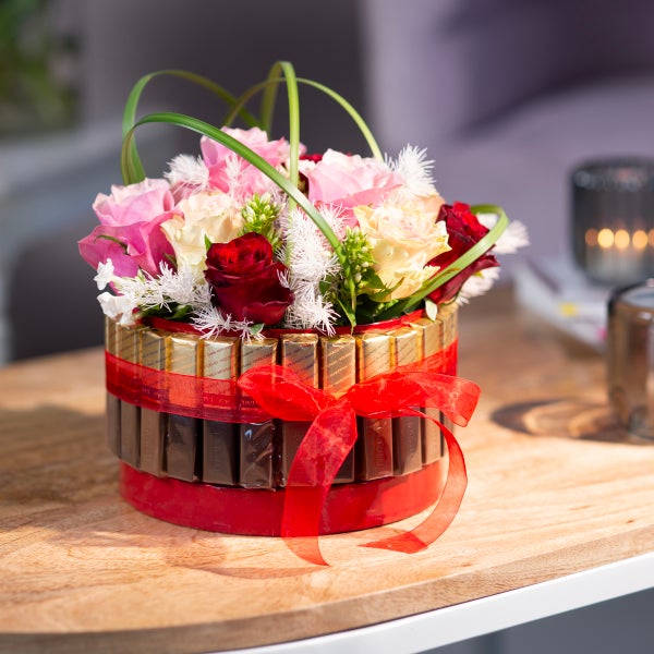 Blumenarrangement in einer mit Pralinen verzierten Box