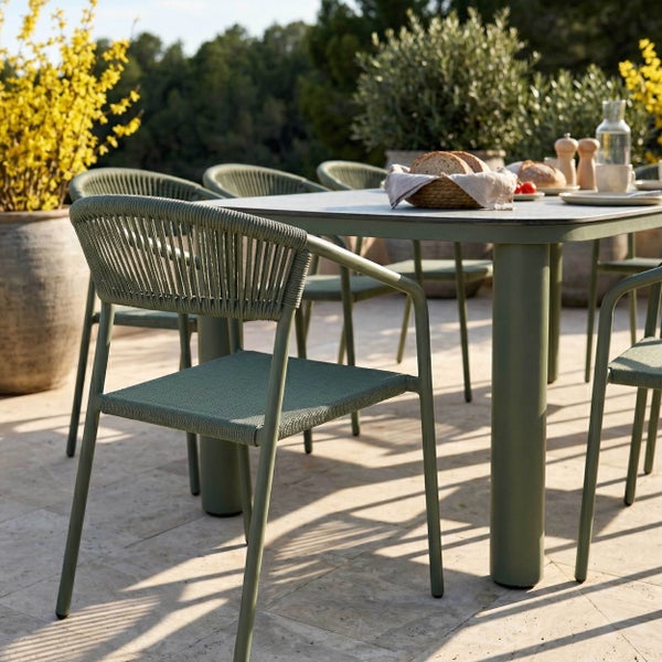 Moderne Garten-Essgruppe bestehend aus grünem Metalltisch und passenden Armlehnenstühlen mit Seilgeflecht auf einer sonnigen Terrasse.