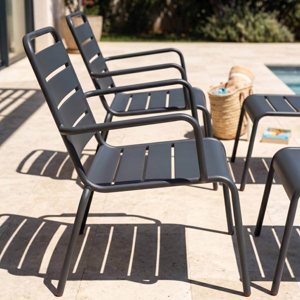 Moderne Gartenstühle aus Metall mit Armlehnen und Lattenstruktur auf einer hellen Terrasse am Pool.