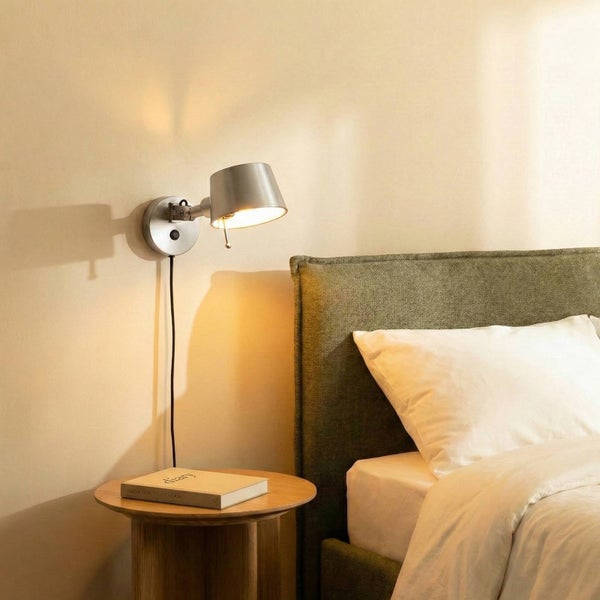 Wandleuchte neben einem Bett montiert, mit Buch auf Nachttisch