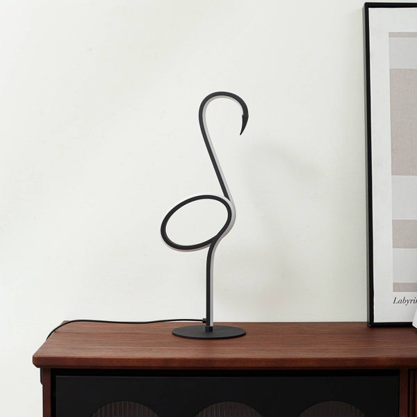 Moderne LED-Tischleuchte in Flamingo-Form auf einem Sideboard aus Holz neben einem gerahmten Bild in einem hellen Raum.