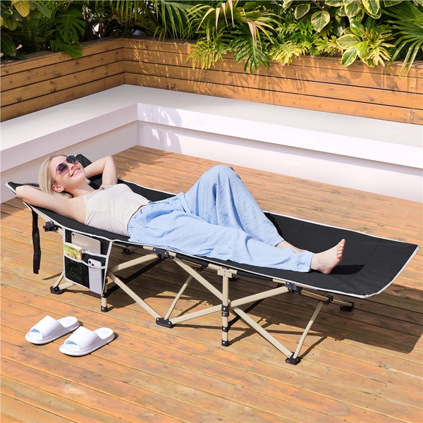 Frau entspannt auf einer schwarzen, zusammenklappbaren Sonnenliege im Freien.
