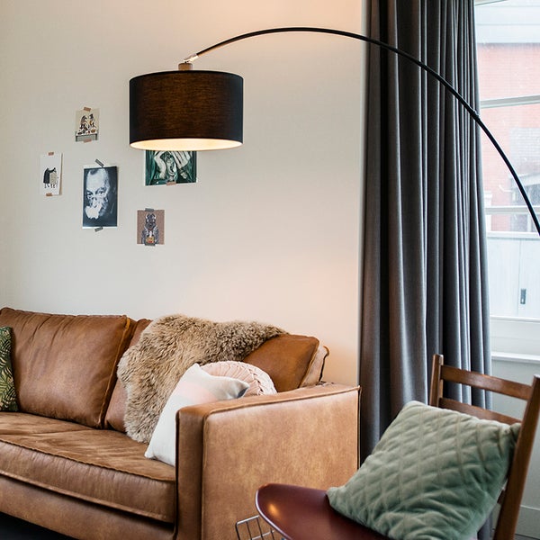 Wohnzimmer mit braunem Ledersofa, Bogenlampe und Wanddekoration