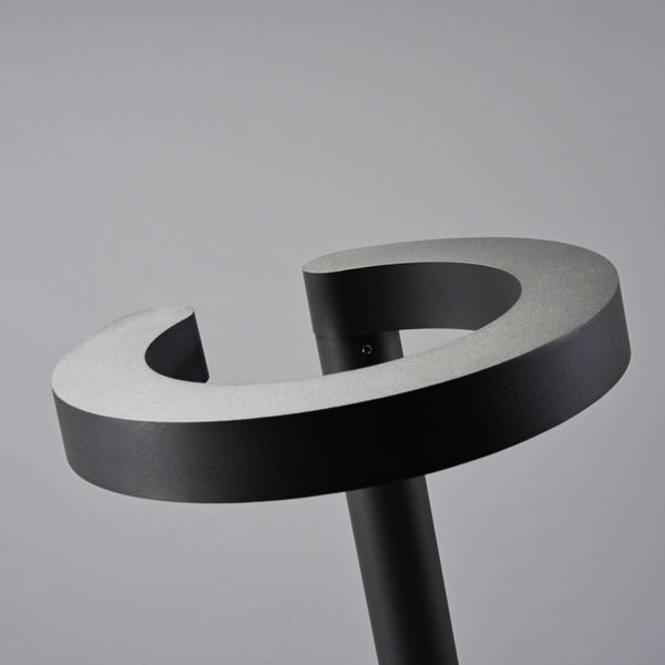 Nahaufnahme einer modernen Außenleuchte mit spiralförmigem Kopf aus dunklem Metall.