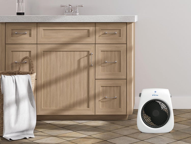 Badezimmer Szene mit Waschtischunterschrank, Wäschekorb mit Handtuch und tragbarem Ventilator