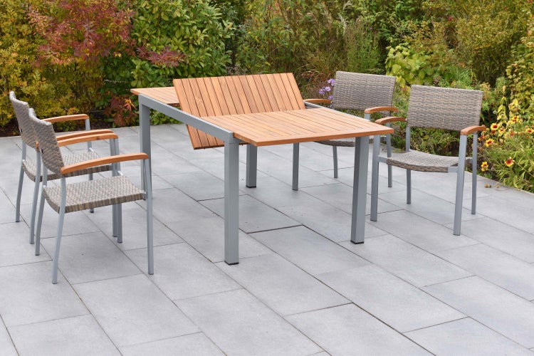 Moderne Garten-Essgruppe auf einer Terrasse mit ausziehbarem Holztisch und vier Geflechtsesseln mit Metallgestell und Holzarmlehnen.