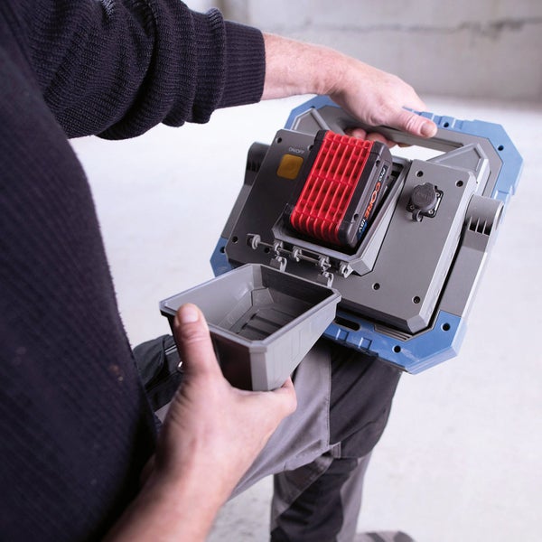 Person öffnet Fach an einer Akku-Baustellenleuchte