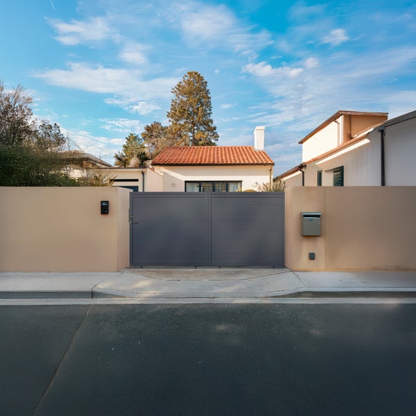 Zweiflügeliges Einfahrtstor aus Metall in Anthrazit mit horizontalen Lamellen, eingebaut zwischen hellen Mauern vor einem Wohnhaus.