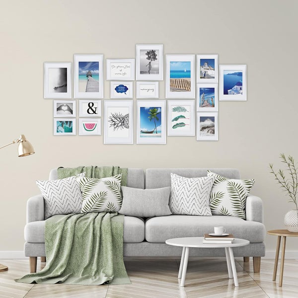 Bilderrahmen Set mit Wanddekoration über einem Sofa mit Kissen und einer Decke in einem modern eingerichteten Wohnzimmer.