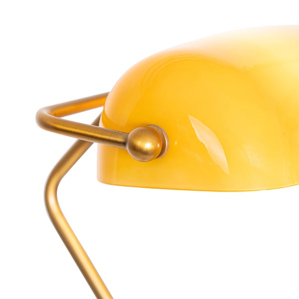 Detailansicht einer gelben Schreibtischlampe mit goldenem Gestell.