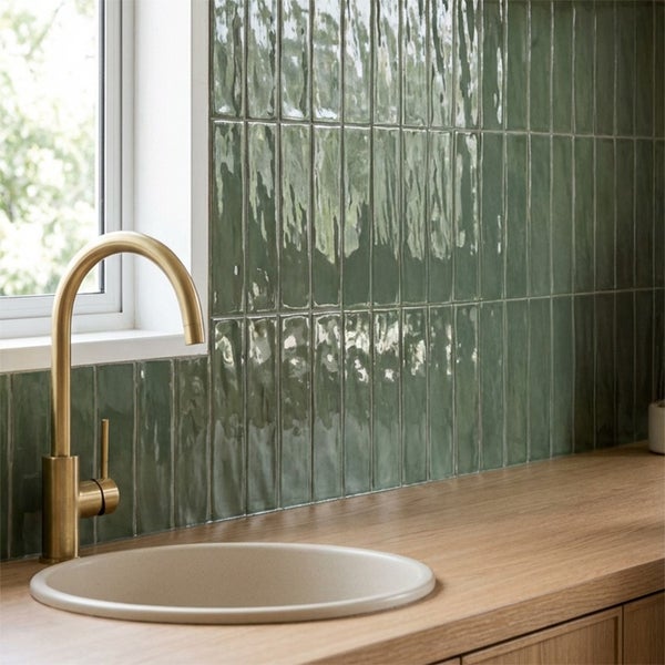 Moderne Küche mit vertikal verlegten glänzenden Wandfliesen, runder Spüle und einem hohen Wasserhahn in Metalloptik auf einer Holz Arbeitsplatte