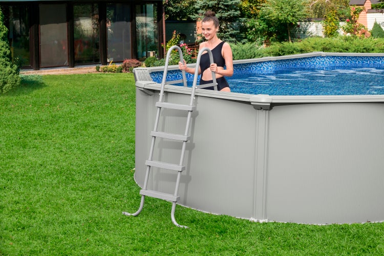 Aufstellpool mit Stahlwand und Poolleiter in einem hellen, gepflegten Garten auf einer Rasenfläche.