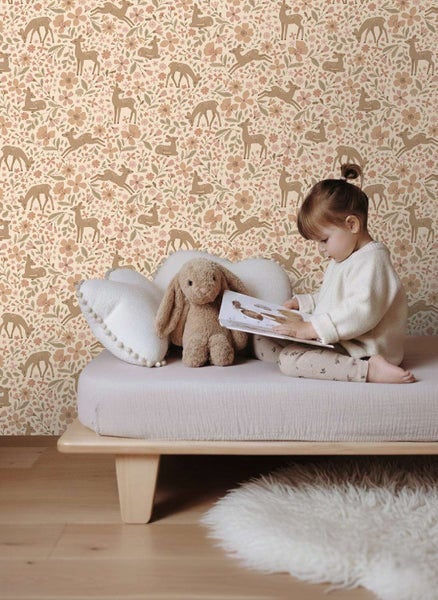 Kind im Zimmer vor einer Vliestapete mit Waldmotiven wie Rehen und Blumen in einer hellen, freundlichen Wohnatmosphäre.