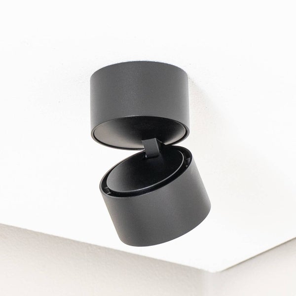 Schwarzer, verstellbarer Aufbaustrahler in zylindrischer Form für die Deckenmontage.