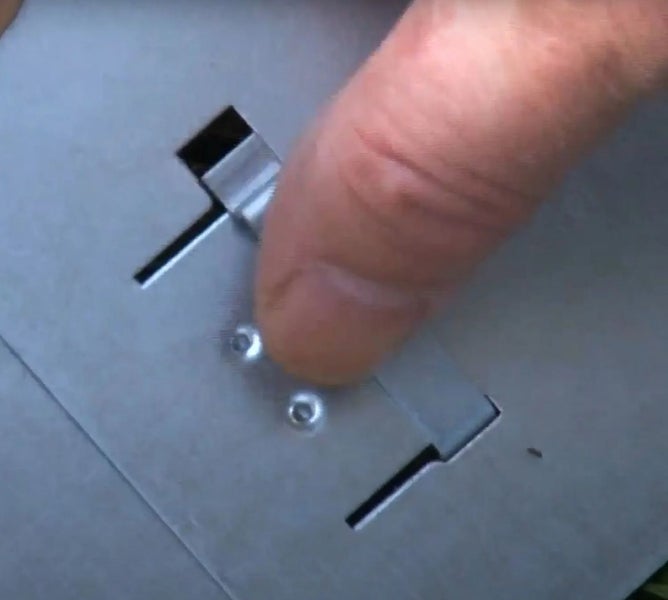 Detailaufnahme einer Metallplatte mit Schlitzen und einer Hand, die einen Schieber bedient.