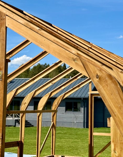 Holzgerüst für ein Gewächshaus im Aufbau im Garten vor einem Wohnhaus