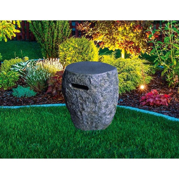Gartensteckdose in Steinoptik auf einer Rasenfläche vor einem bepflanzten Beet in einem hellen und organisierten Garten.