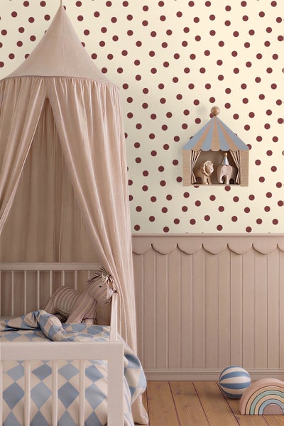Kinderzimmer mit gepunkteter Tapete, Wandpaneelen mit Wellenkante und einem Gitterbett mit Betthimmel. Ein Zirkus-Wandregal und Spielzeug sind sichtbar.