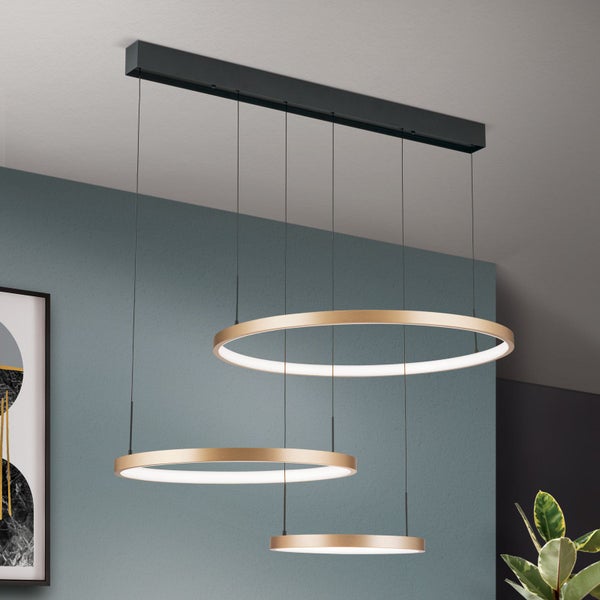 Moderne LED Pendelleuchte mit drei runden Ringen in Metalloptik an einer Deckenhalterung in einem Wohnraum.