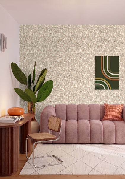 Wohnzimmer im Retro-Stil mit floral gemusterter Tapete, einem rosa Stoffsofa, einem Schreibtisch aus Holz und einer großen Zimmerpflanze.