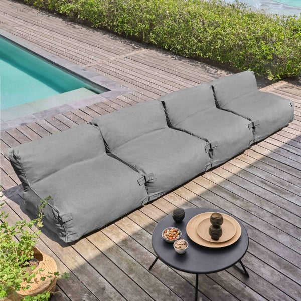 Modulares graues Outdoor-Lounge-Sofa auf einer Holzterrasse neben einem Pool mit kleinem Beistelltisch.