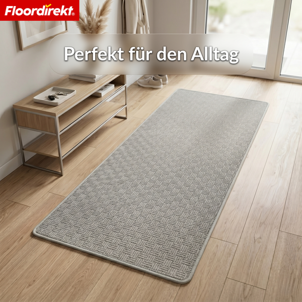 Teppichläufer mit Webstruktur in einem hellen Flur mit Holzfußboden und Sideboard. Floordirekt Logo.