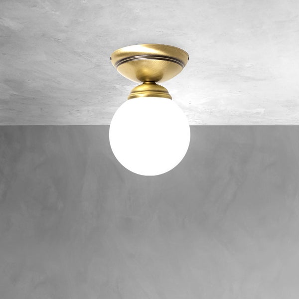 Deckenleuchte mit runder, weißer Glaskugel und goldfarbener Halterung
