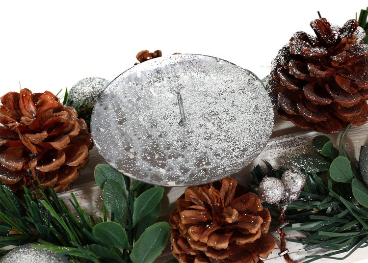 Dekorative Anordnung mit Stumpenkerze, Tannenzapfen und Grünzeug für weihnachtliche Dekoration