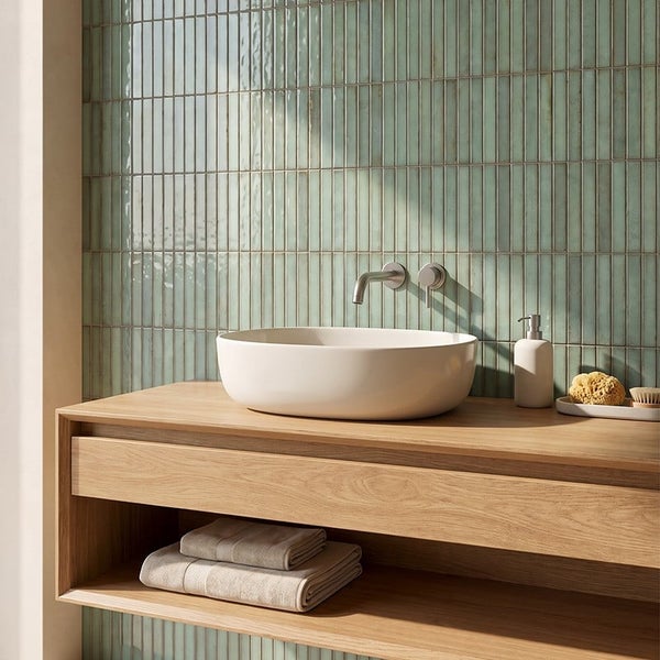 Badezimmer mit hängendem Waschtisch aus Holz, weißem Aufsatzwaschbecken und Wandfliesen in schmalem Riegelformat.