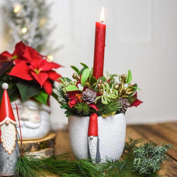 Weihnachtsdekoration mit Kerze, Blumen und Zwergen in einem weißen Topf