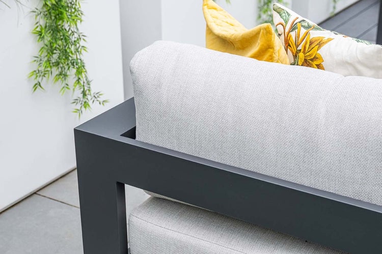 Detailansicht eines Gartensofas mit Aluminiumrahmen, grauen Sitzkissen und dekorativen Zierkissen im Freien.