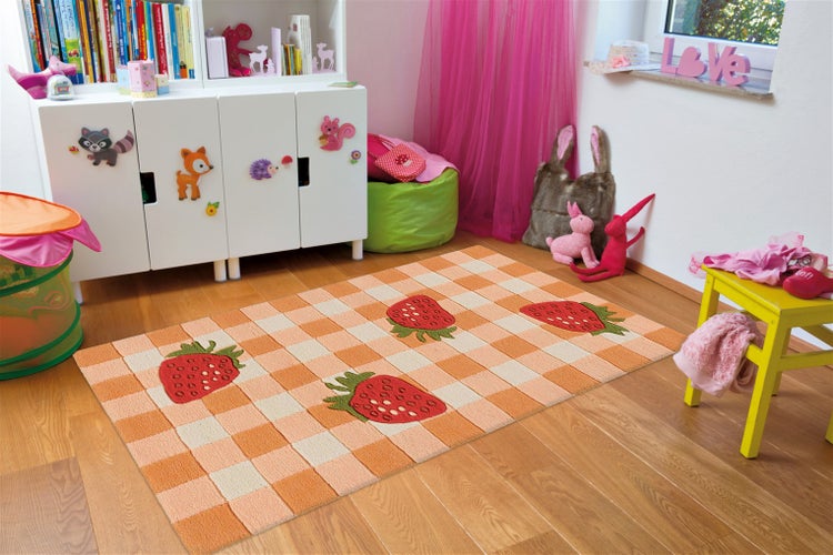 Kinderzimmer mit Holzboden und einem rechteckigen Teppich im Schachbrettmuster mit Erdbeermotiven in einem verspielten Einrichtungsstil.