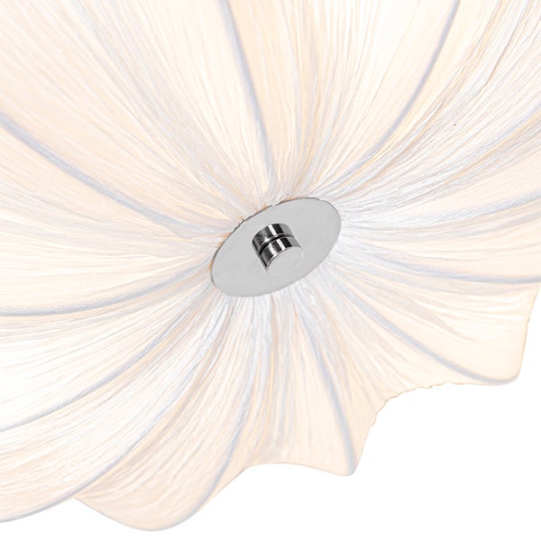 Nahaufnahme eines Deckenleuchten-Schirms aus weißem, plissiertem Stoff mit einer silbernen Metallhalterung in der Mitte.