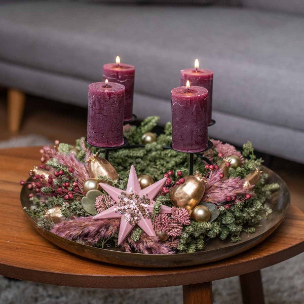 Dekorativer Adventskranz mit Kerzen, Sternen und Kugeln auf einem Tisch