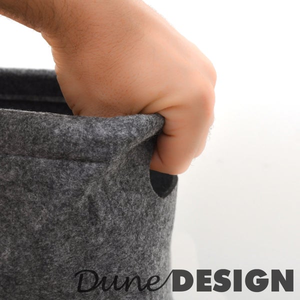Hand greift in einen runden Filzkorb von Dune Design mit Griffloch