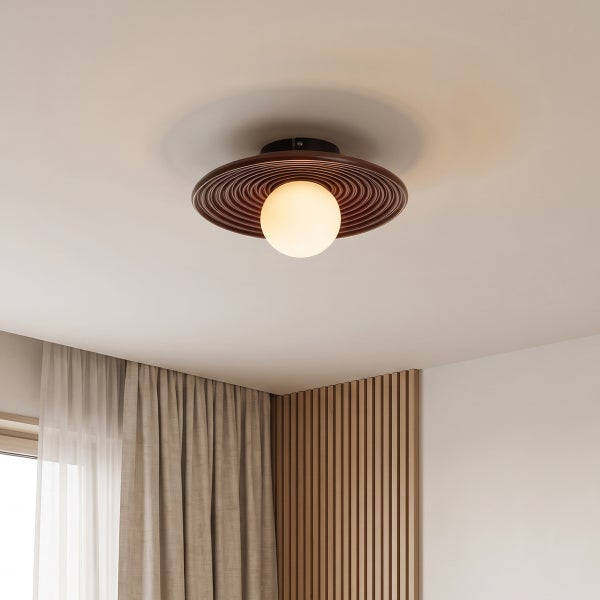 Moderne Deckenleuchte mit kugelförmigem Leuchtmittel und kreisförmigem Designelement in einem Raum mit Vorhängen und Holzlamellenwand.
