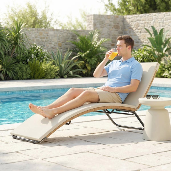 Mann auf ergonomischer Gartenliege mit hellem Polster und dunklem Metallgestell an einem Pool im Garten mit mediterranen Pflanzen.