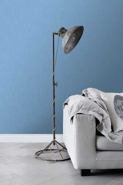 Stehlampe im Industriedesign neben einem Sofa in einem hellen Raum.