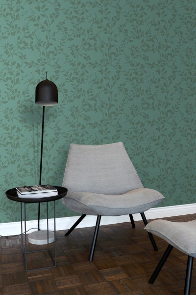 Einrichtungsszene mit Sessel, Stehlampe, Beistelltisch und grüner Blättertapete