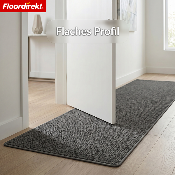 Floordirekt Logo. Flacher Teppichläufer mit Struktur unter einer Zimmertür auf Holzboden im hellen Flur.