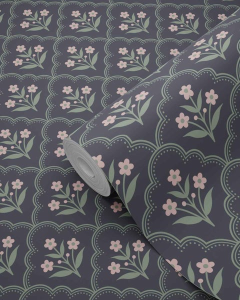 Dunkle Mustertapete mit rosa Blumen und grünen Blättern in geschwungenen Rahmen, eine teilweise ungerollte Tapetenrolle.