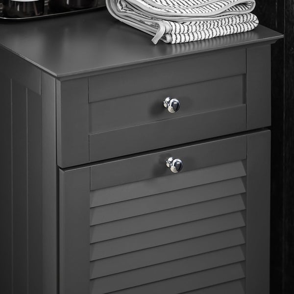 Grauer Badezimmerschrank mit zwei Schubladen und einer Tür mit Lamellenstruktur