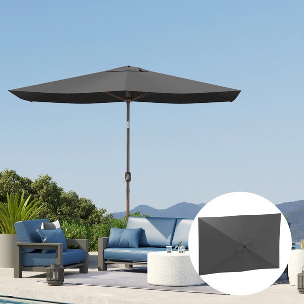 Dunkelgrauer rechteckiger Sonnenschirm auf einer hellen Terrasse mit blauen Loungemöbeln und weißem Tisch vor einer Gebirgskulisse.