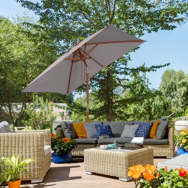 Gartenlounge mit Polyrattan-Ecksofa, Sessel und Tisch auf Holzterrasse unter einem großen rechteckigen grauen Sonnenschirm mit Holzgestell.