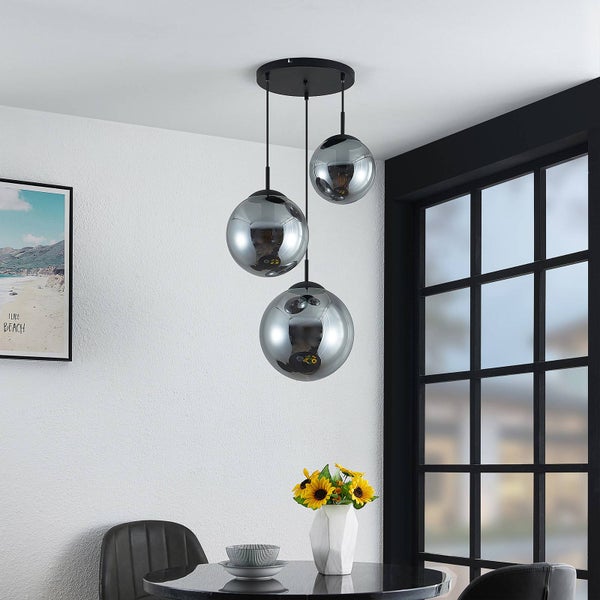 Dreiflammige Pendelleuchte mit rauchfarbenen Glaskugeln in verschiedenen Höhen über einem Esstisch in modernem Ambiente.