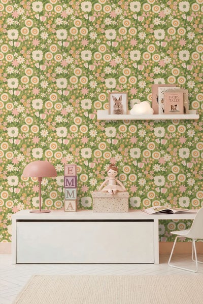 Florale Tapete mit Blumenmuster auf grünem Hintergrund in einem hellen Kinderzimmer mit weißem Schreibtisch und rosa Lampe.