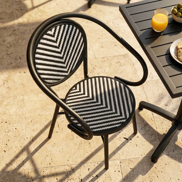 Bistro-Gartenstuhl mit Armlehnen, schwarzes Metallgestell und schwarz-weiß geflochtene Sitzfläche und Rückenlehne mit Zickzack-Muster.